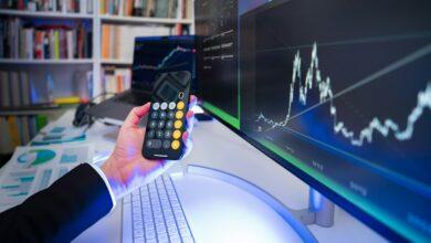 A man holding a remote control in front of a computer
