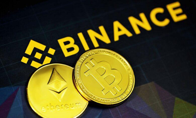 two gold bitcoins sitting next to a binance sign