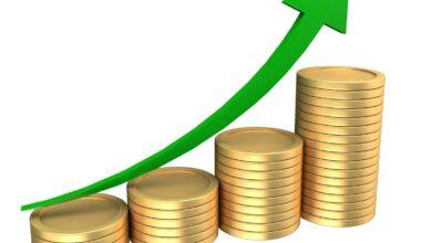 Stacks of coins with an upward trending green arrow