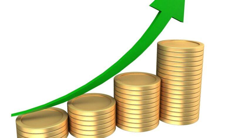 Stacks of coins with an upward trending green arrow